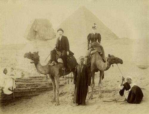 Fotografía utilizando la técnica de la albúmina, en torno a 1890, que representa una vista de dos turistas, montados en camello frente a la Esfinge de Gizeh y la Pirámide de Keops. Se aprecian varios personajes autóctonos. Autor: desconocido. Colección particular del autor.